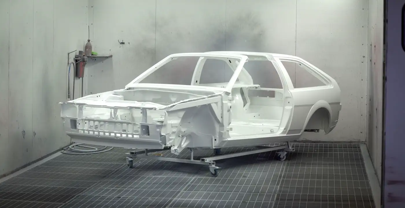 Illustrative photo of a primed car body in a spray booth. Not the Russell's workshop and not their staff.